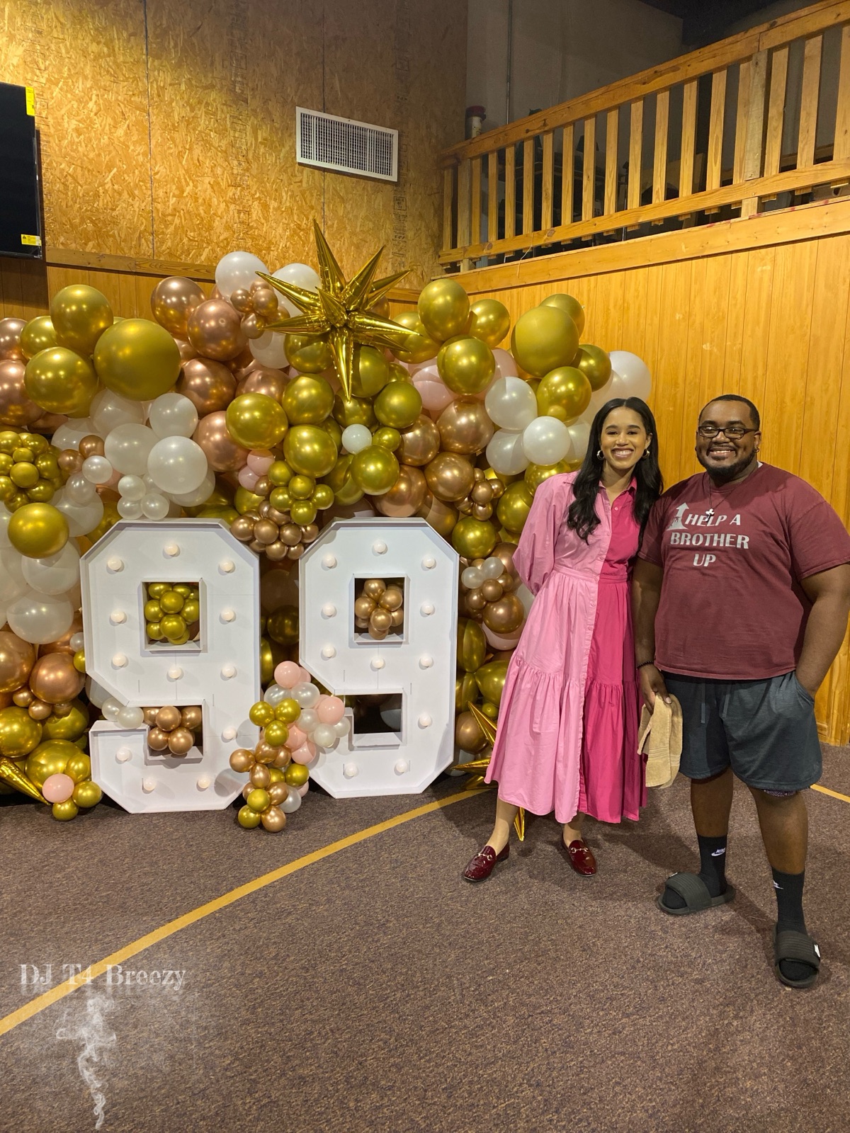 DJ T4 Breezy with a guest in front of a gold and white balloon wall with large 99 marquee numbers